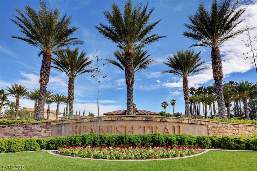 7995 Rio Rico Drive Las Vegas, NV 89113 - Photo 75 of 92 An inviting community entrance features a stone wall sign, vibrant landscaping, and towering palm trees.