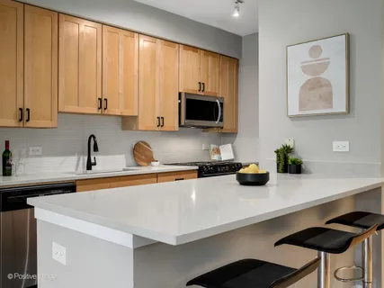 a kitchen with stainless steel appliances a sink a microwave a refrigerator and cabinets