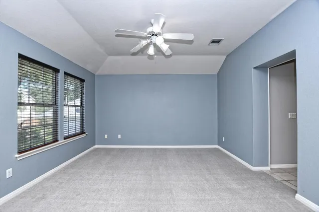 an empty room with a chandelier fan and windows