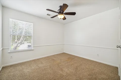 a view of a livingroom with a ceiling fan & windows