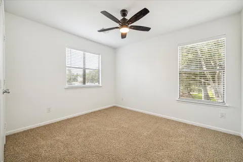 an empty room with a window and a ceiling fan