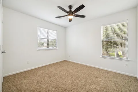an empty room with a window and a ceiling fan