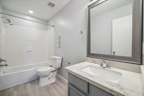 a bathroom with a granite countertop sink a toilet and shower