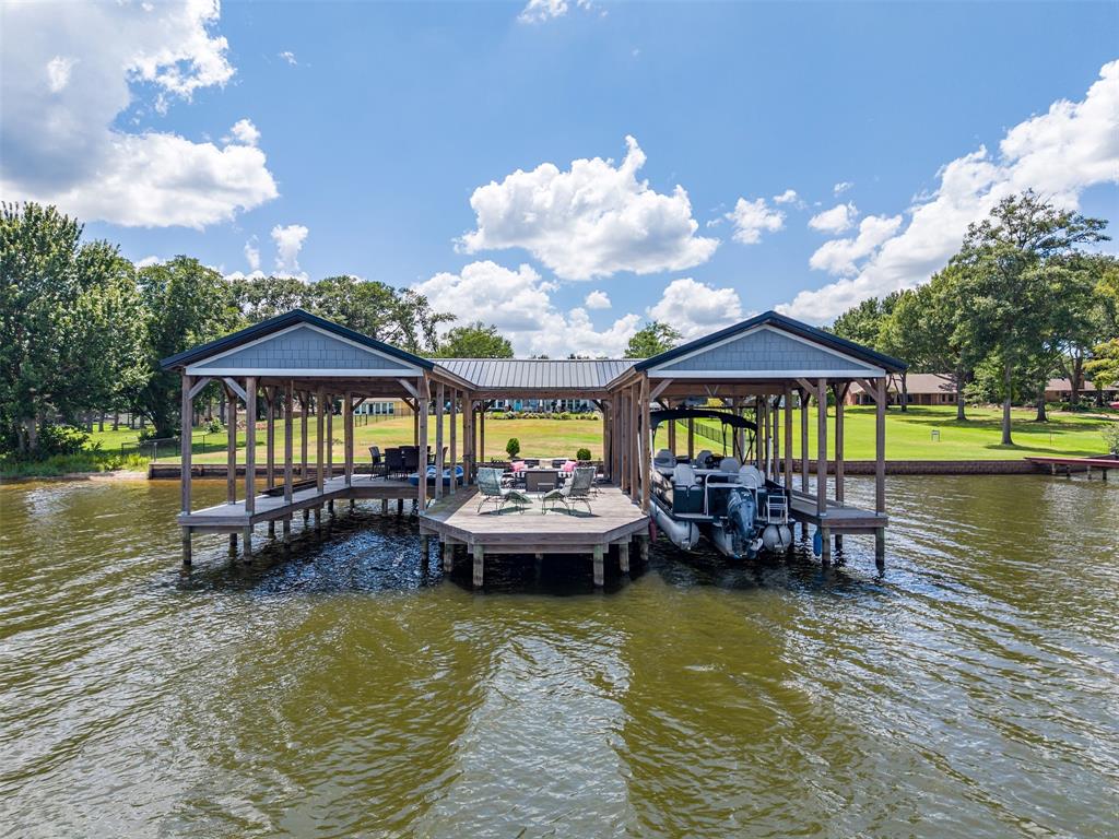 16241 Big Oak Bay Road Tyler, TX 75707 - Photo 40 of 40 Expansive double boat dock featuring two covered slips, a central open deck area, wood pilings, and a metal roof