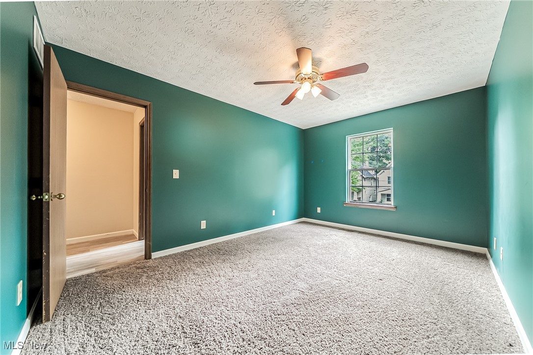 761 Garfield Street Akron, OH 44310 - Photo 22 of 31 Empty room featuring carpet, ceiling fan, and a textured ceiling