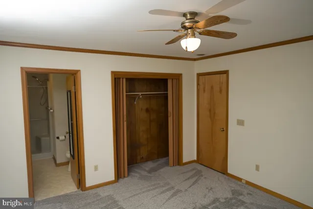 an empty room with closet and a chandelier fan