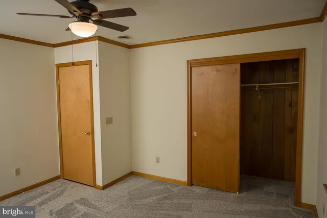 an empty room with a ceiling fan and carpet