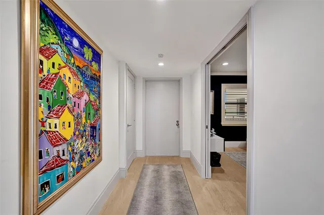 a view of a hallway with painting on the wall and a potted plant