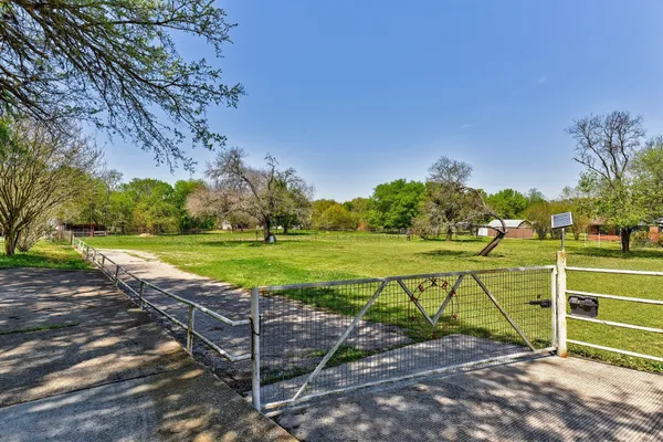 a view of a tennis ground with large trees