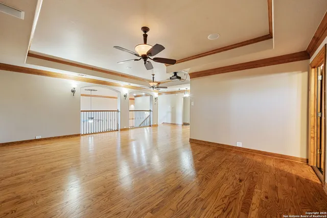 a view of a room with wooden floor ceiling fan and windows