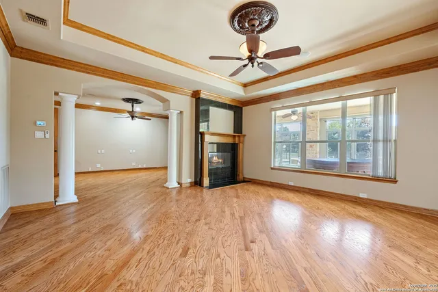 a view of an empty room with a window and wooden floor
