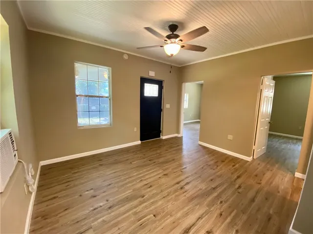 a view of an empty room with wooden floor and a window