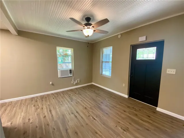 a view of an empty room with wooden floor and a window