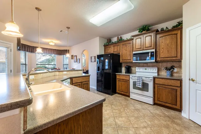 a kitchen with stainless steel appliances granite countertop a refrigerator a stove and a sink with wooden floor