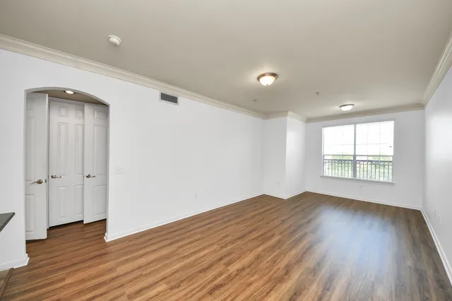an empty room with wooden floor and windows