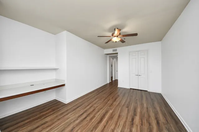 a view of a room with wooden floor and a ceiling fan