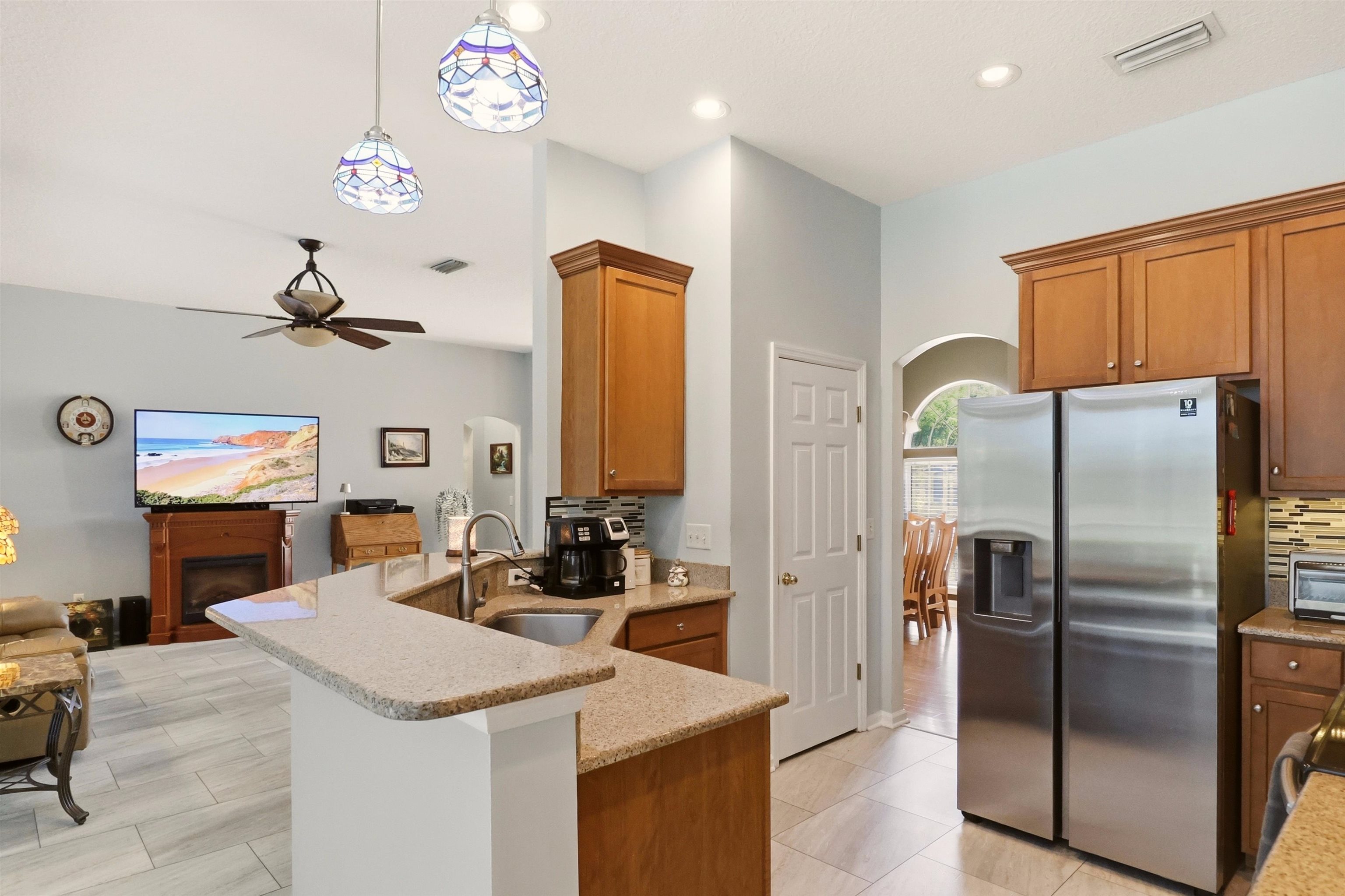 273 Whisper Ridge Drive St. Augustine, FL 32092 - Photo 18 of 44 Kitchen with arched walkways, stainless steel refrigerator with ice dispenser, light stone counters, and a fireplace