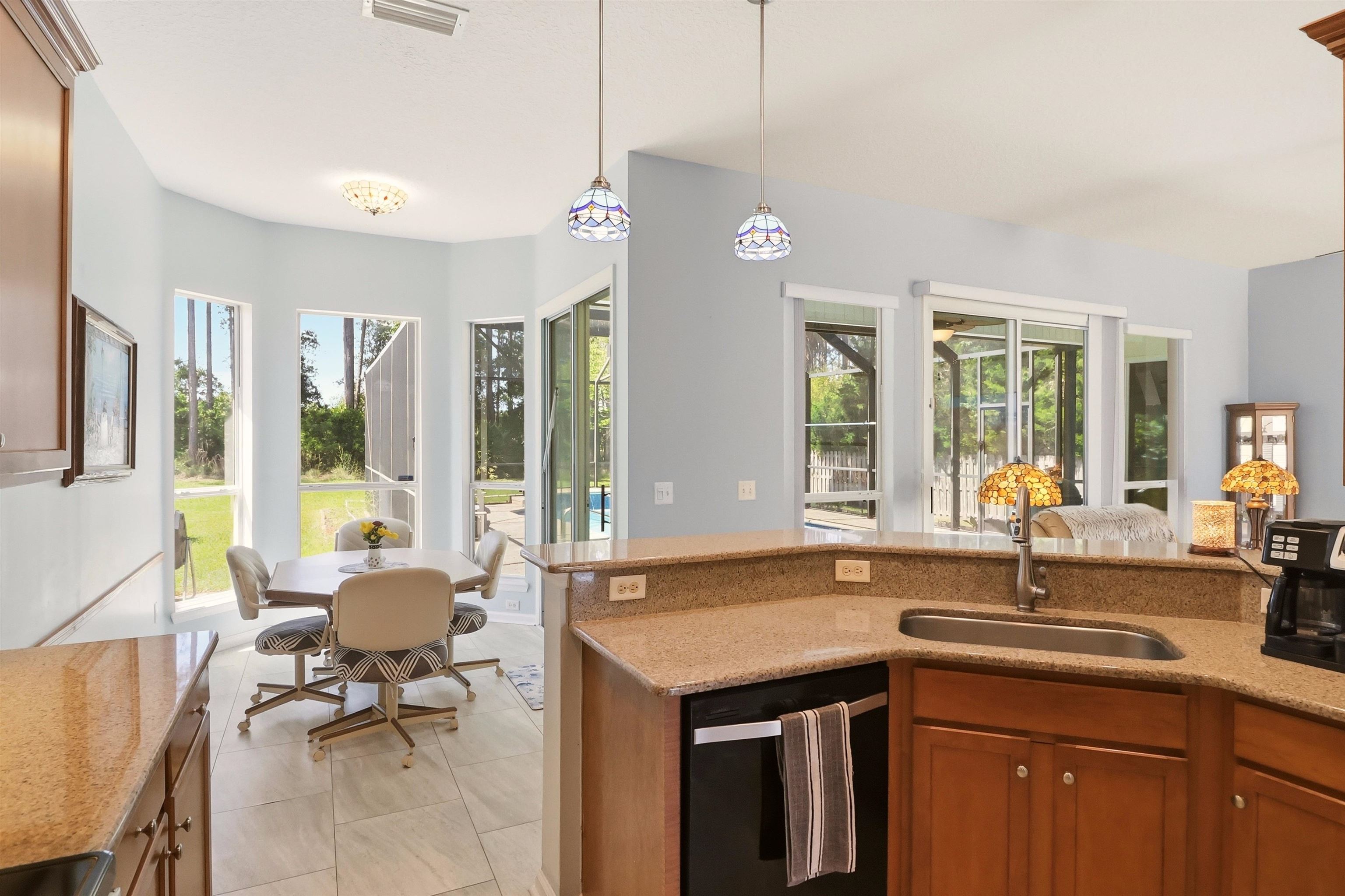 273 Whisper Ridge Drive St. Augustine, FL 32092 - Photo 19 of 44 Kitchen with light stone counters, black dishwasher, wood finish cabinetry, decorative light fixtures, and plenty of natural light