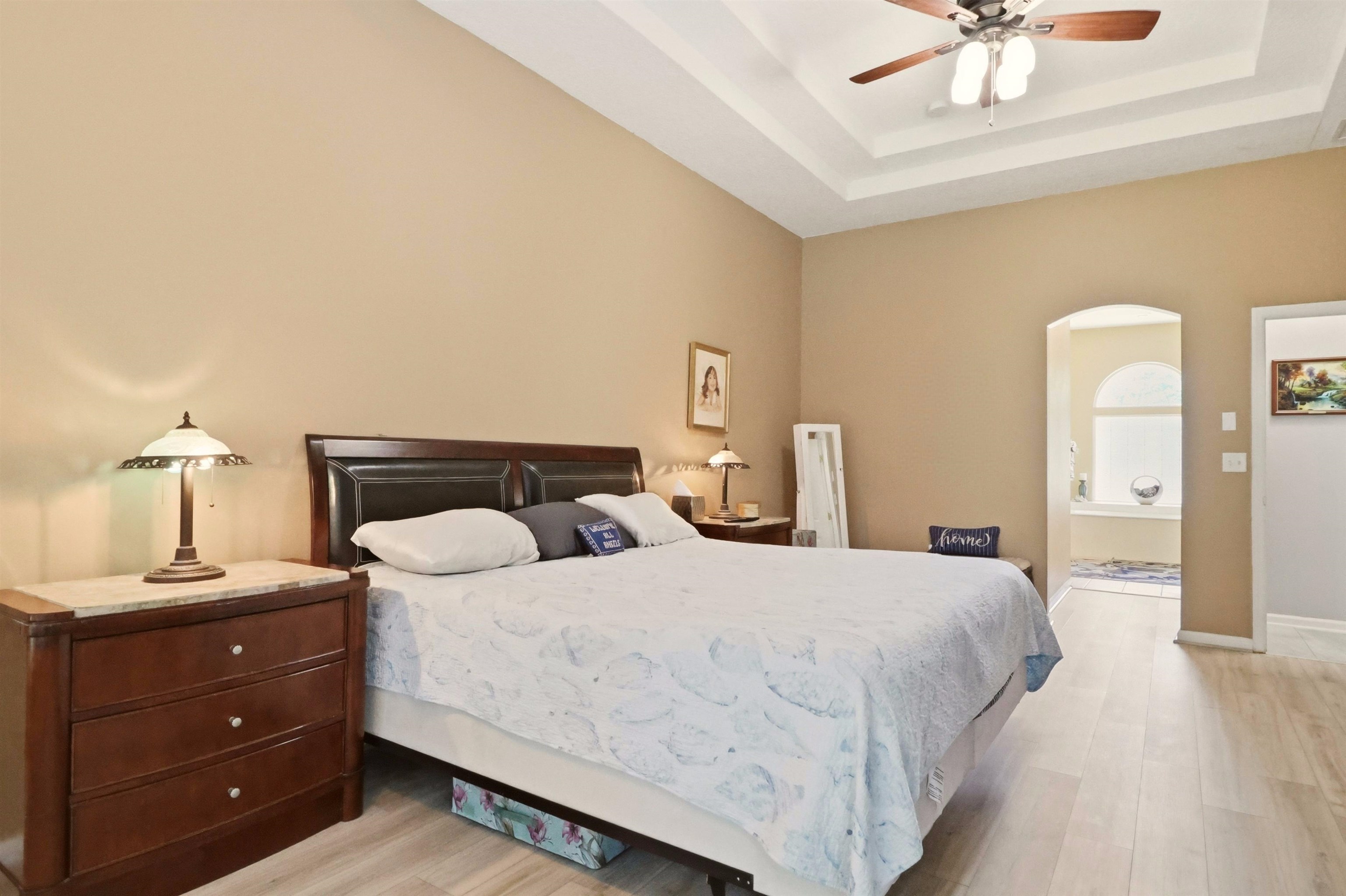 273 Whisper Ridge Drive St. Augustine, FL 32092 - Photo 24 of 44 Bedroom featuring light wood-type flooring, arched walkways, a ceiling fan, and a raised ceiling