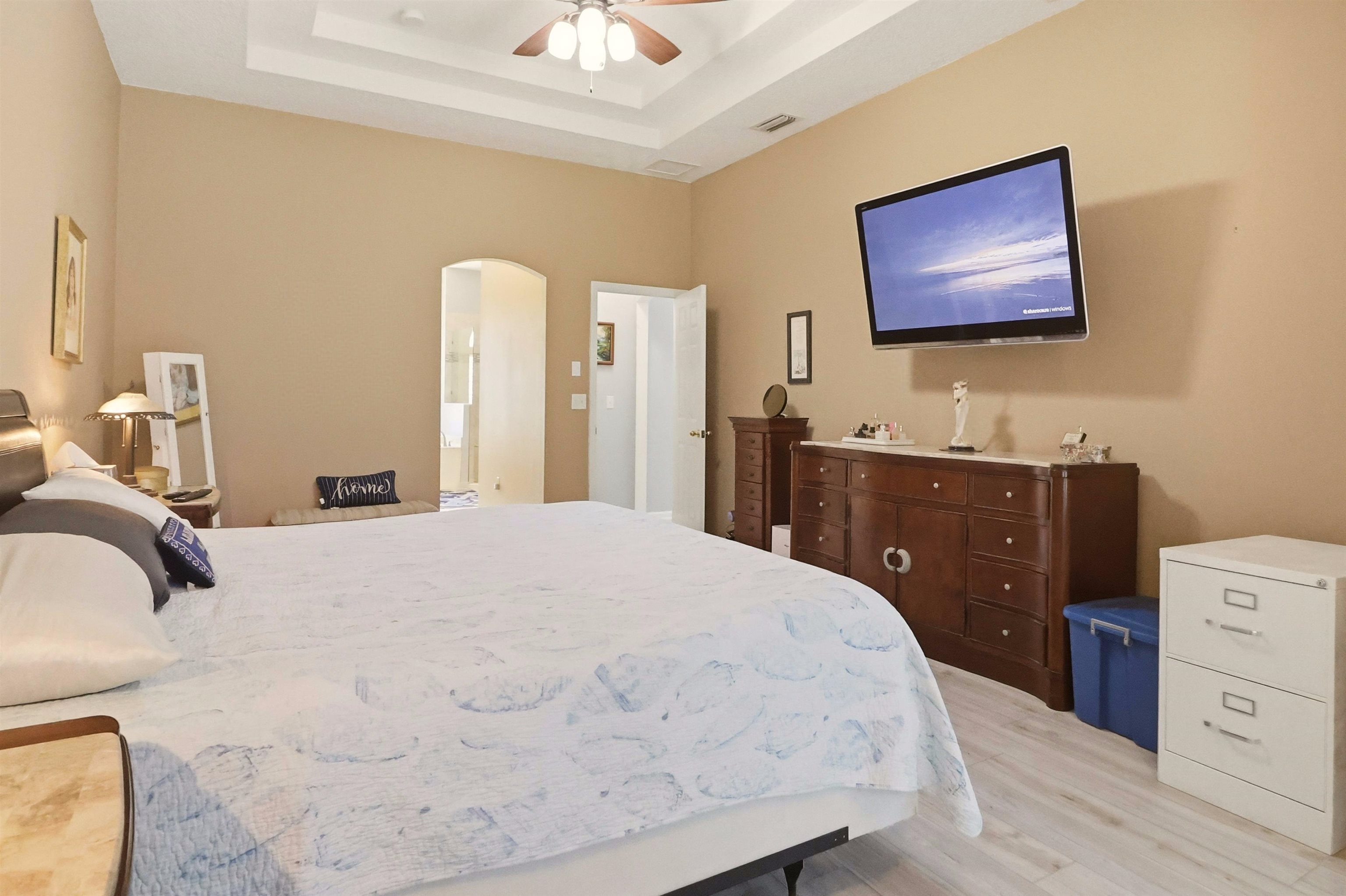 273 Whisper Ridge Drive St. Augustine, FL 32092 - Photo 25 of 44 Bedroom with light wood-type flooring, arched walkways, a tray ceiling, and a ceiling fan