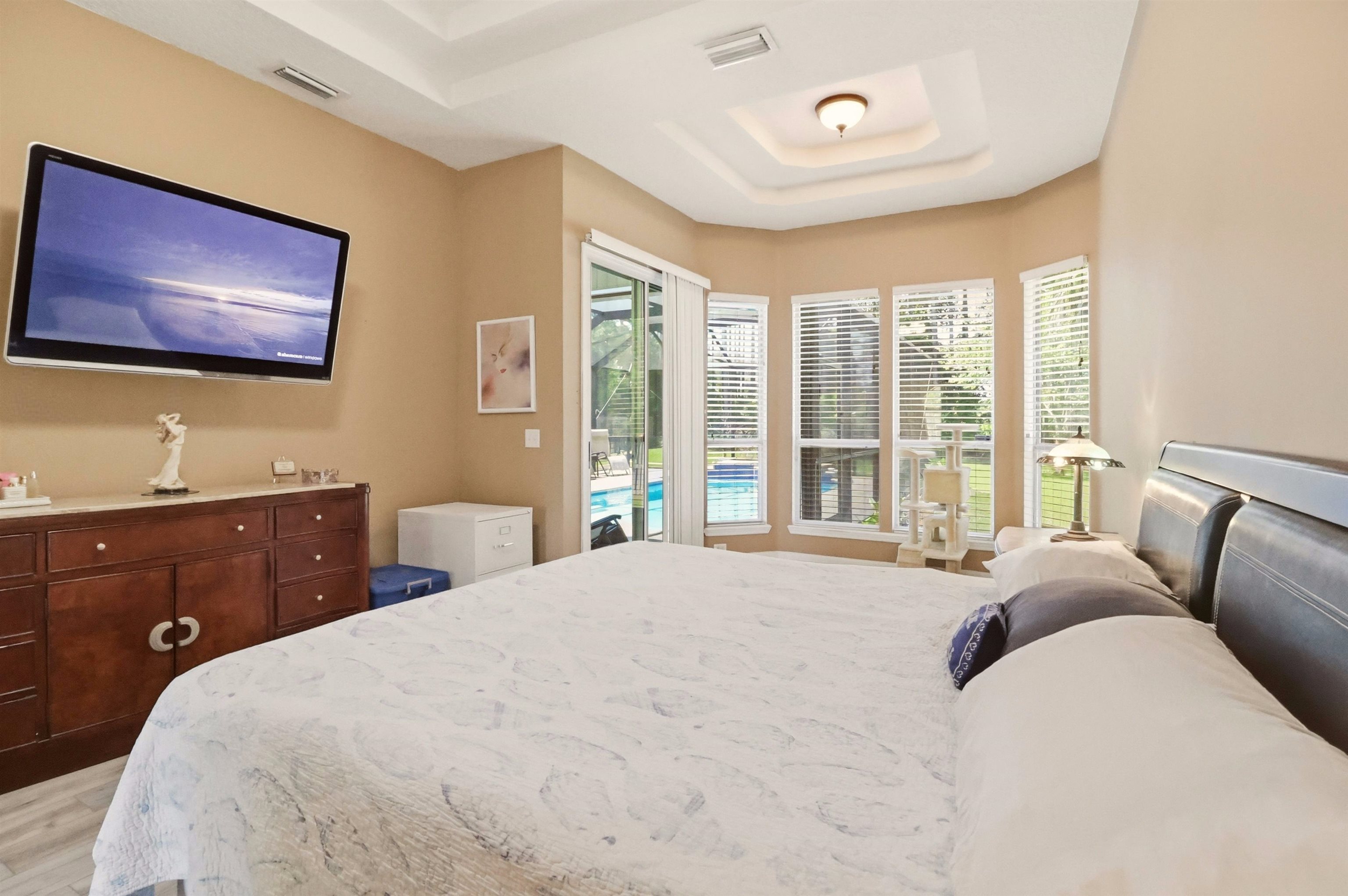 273 Whisper Ridge Drive St. Augustine, FL 32092 - Photo 26 of 44 Bedroom with a tray ceiling, sitting area, access to outside, and light LVP flooring