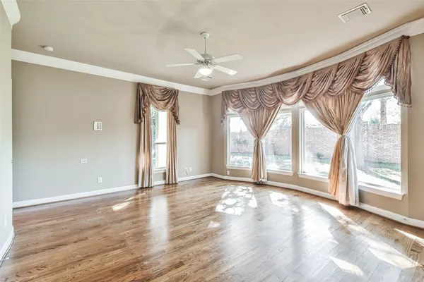 a view of an empty room with a window and wooden floor