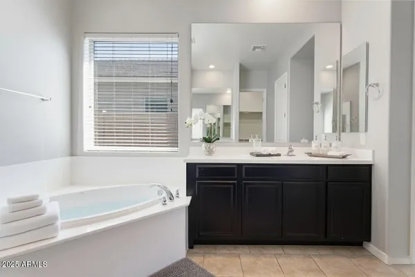 a bathroom with a bathtub sink vanity and mirror