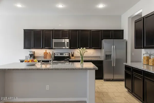 a kitchen with granite countertop a refrigerator and a stove top oven