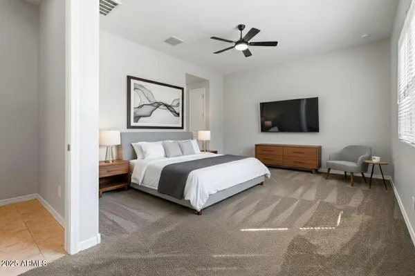 a spacious bedroom with a bed a couch and a flat screen tv