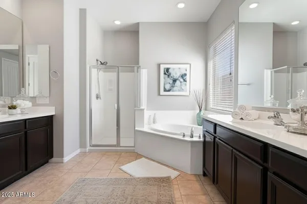 a spacious bathroom with a double vanity sink a large mirror and a bathtub