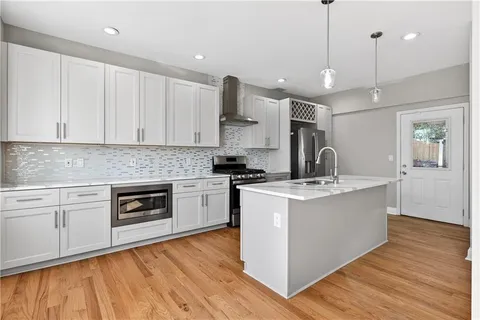 a kitchen with stainless steel appliances granite countertop a sink a stove and a wooden floors
