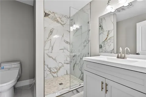 a bathroom with a granite countertop sink a toilet and shower