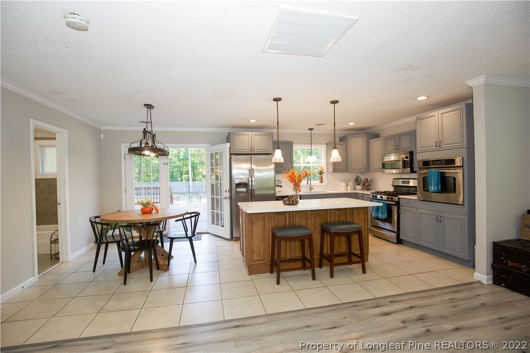 321 Pinecrest Court Road Aberdeen, NC 28315 - Photo 18 of 50 a dining room with stainless steel appliances kitchen island granite countertop a table chairs and a living room view