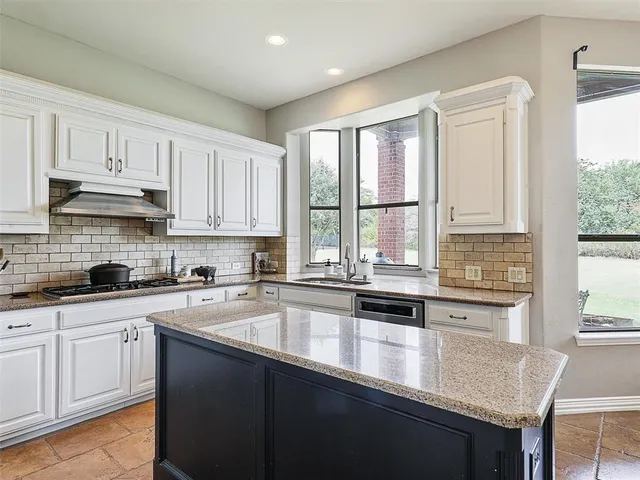 a kitchen with stainless steel appliances granite countertop a sink a stove and cabinets