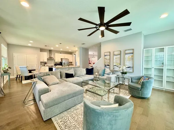 a living room with furniture kitchen view and a large window