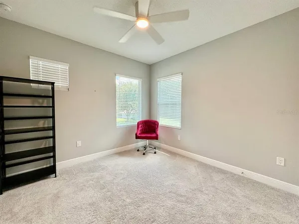 an empty room with a chandelier fan and windows