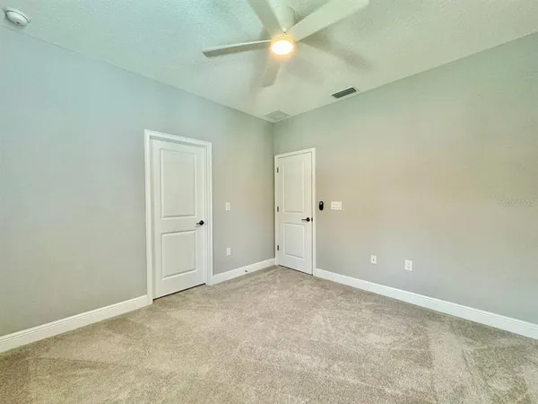 an empty room with closet and fan