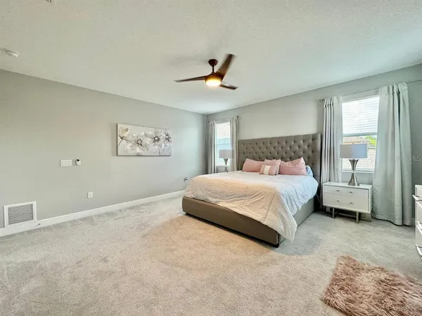 a bedroom with a large bed and a chandelier fan