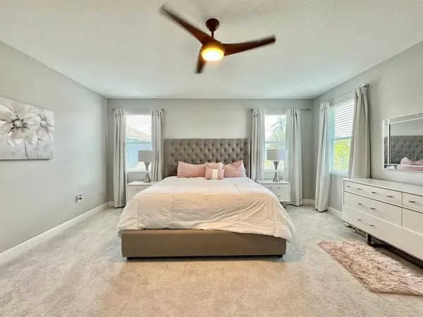 a spacious bedroom with a large bed and a chandelier fan