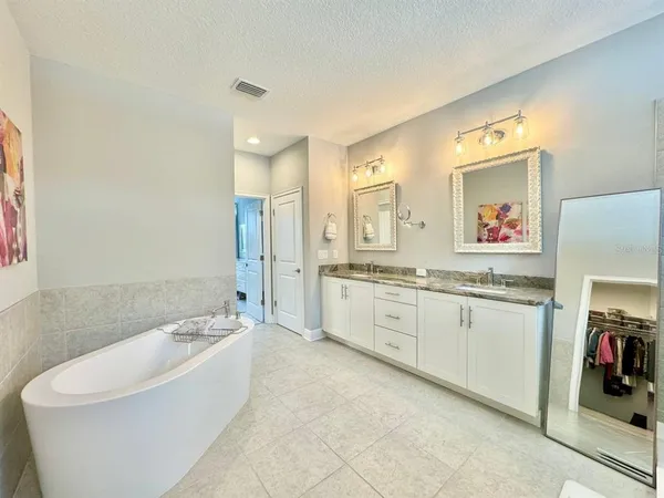 a spacious bathroom with a tub sink and mirror