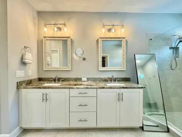 a bathroom with a granite countertop double vanity sink and a mirror