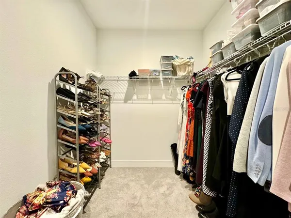 a view of walk in closet with clothes and shoes