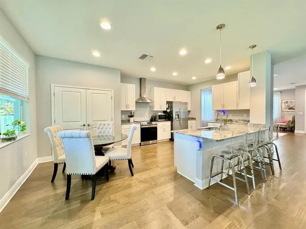 a kitchen with stainless steel appliances kitchen island granite countertop a table chairs sink and cabinets