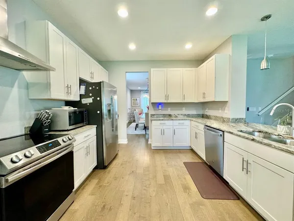a kitchen with stainless steel appliances kitchen island granite countertop a stove a sink dishwasher and a refrigerator