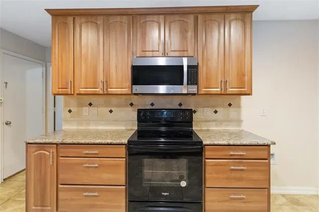 a kitchen with granite countertop wooden cabinets and a stove top oven