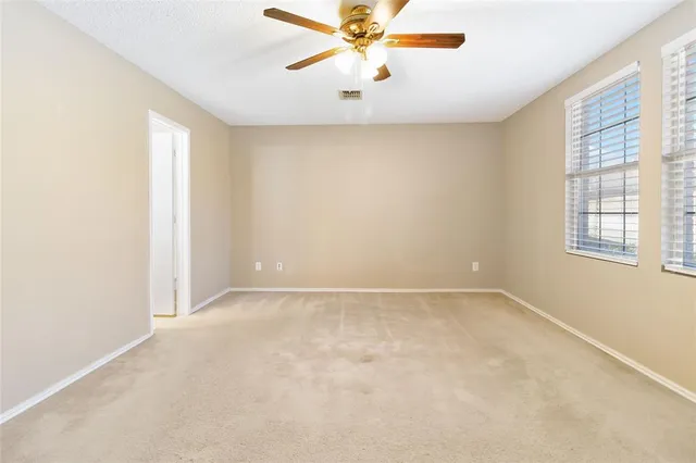 an empty room with a window and a fan