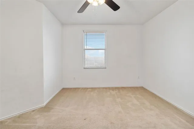 an empty room with a window and a fan