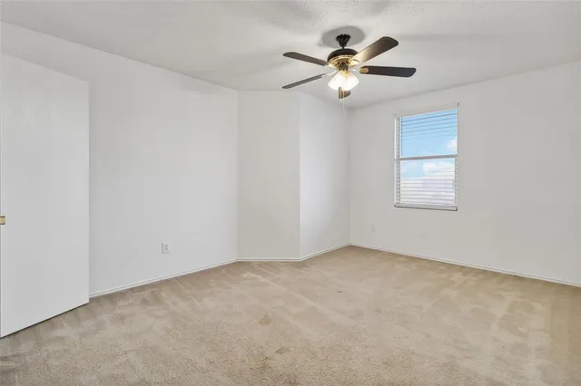 an empty room with chandelier fan and windows