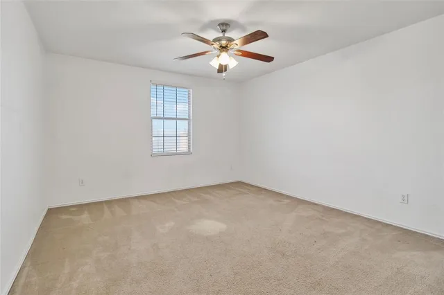 an empty room with chandelier fan and windows