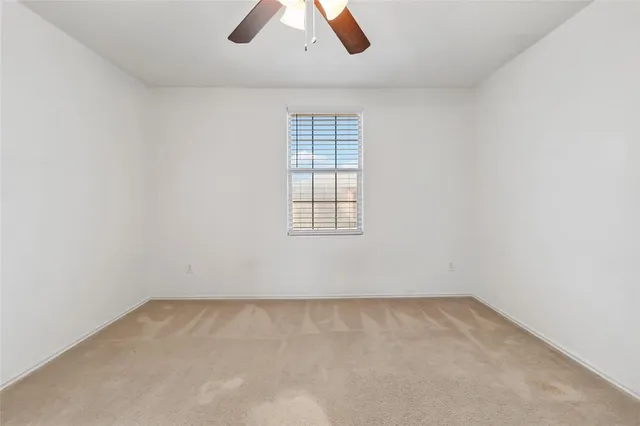 an empty room with ceiling fan and window